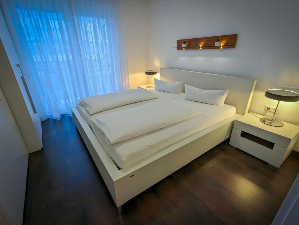 un letto bianco con lenzuola e cuscini bianchi in una camera da letto di Golf & Wellness Suite Bad Bellingen Apartment 5-9 a Bad Bellingen