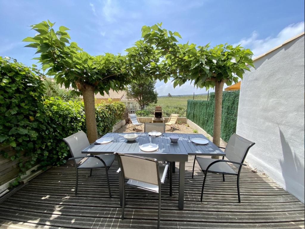 une table et des chaises sur un patio arboré dans l'établissement Appartement avec jardin et piscine collective 5SANT8, à Saint Pierre La Mer