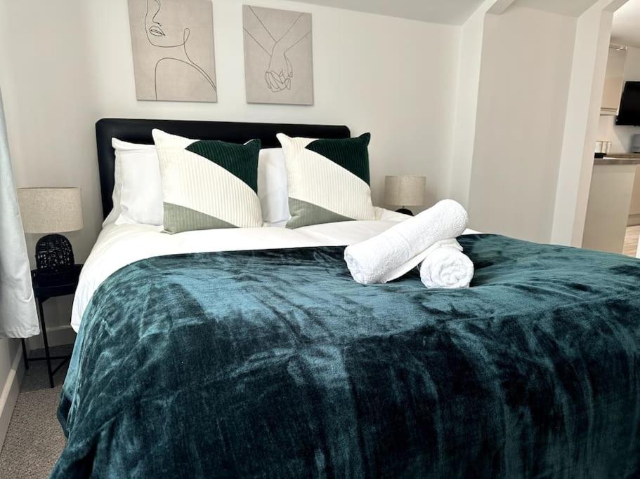 Un dormitorio con una gran cama verde con toallas. en Cosy 1 Bedroom Apartment In Cardiff, en Cardiff