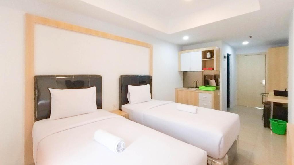 um quarto com duas camas e uma cozinha em Brand New Studio at De Prima Apartment Medan By Travelio em Medan