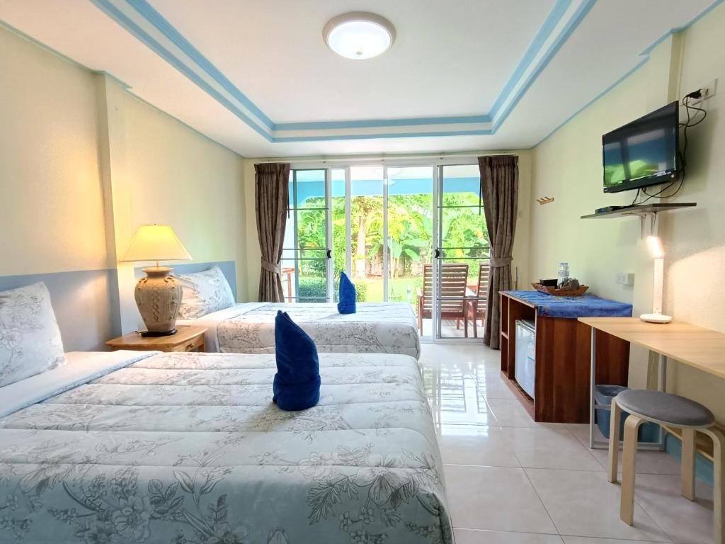 a hotel room with two beds and a television at Forever Kohmook Bungalows in Koh Mook