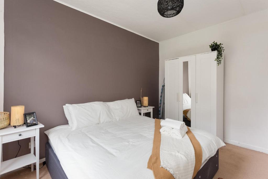 um quarto com uma cama com lençóis brancos e um espelho em Stunning 2 bed apartment Free Parking em Edimburgo