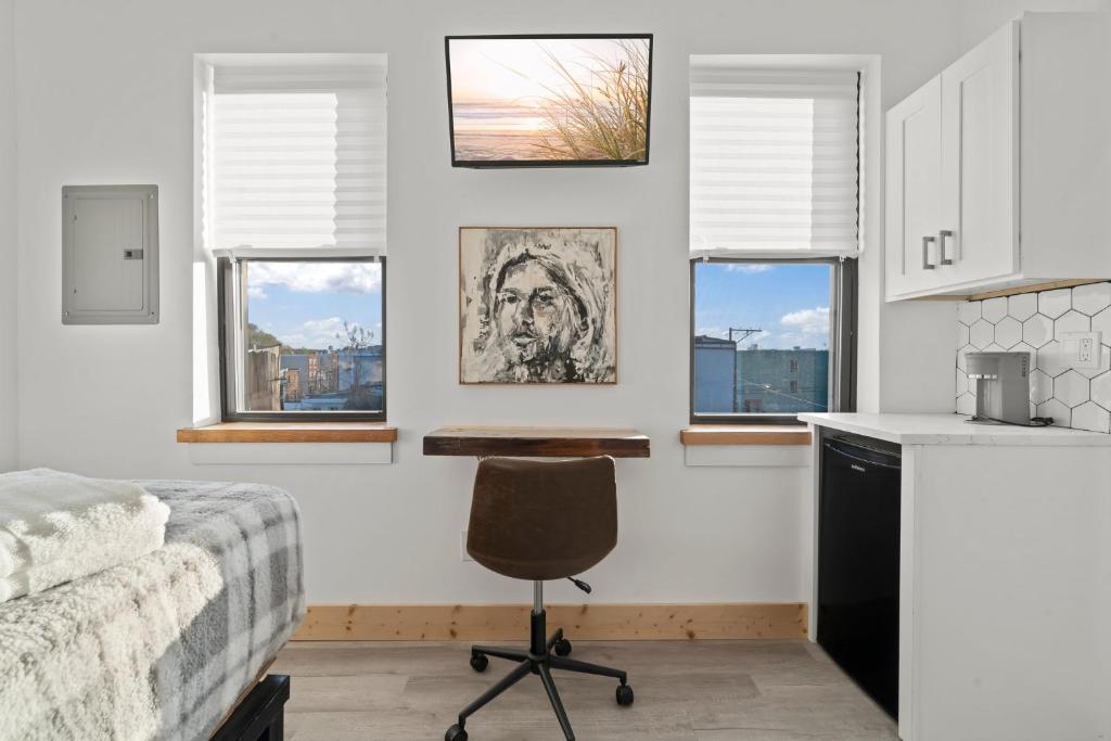 a bedroom with a desk and a chair and windows at Goodseed Suites Philadephia Center in Philadelphia