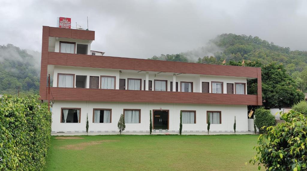 a large white building with a red roof at Bala Shankar Resort Kujarwal Group in Haldwāni