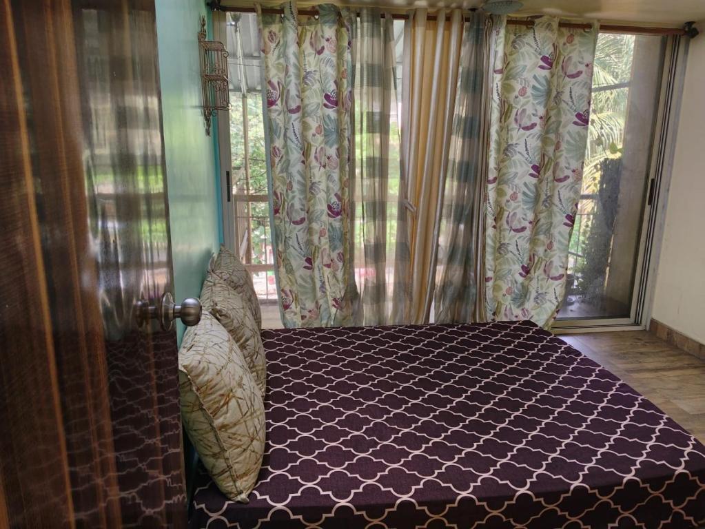 a bedroom with a bed and a window with curtains at Excelol Home Stay in Thane