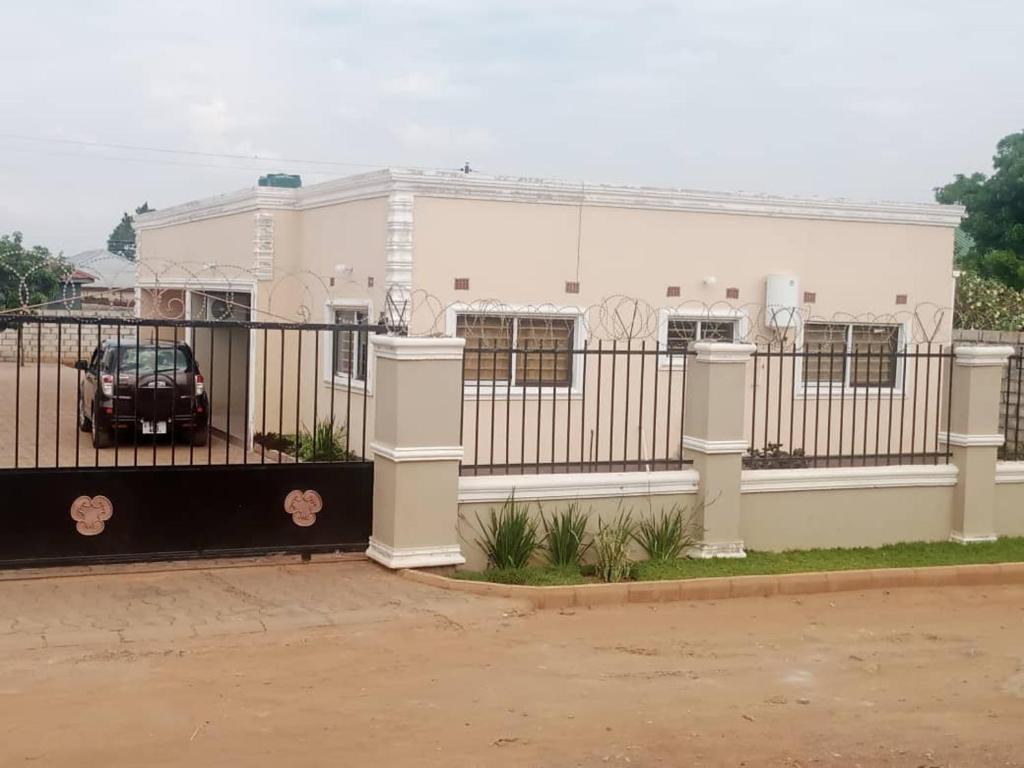 a fence with a car parked in front of a building at Edmut Apartments in Lusaka