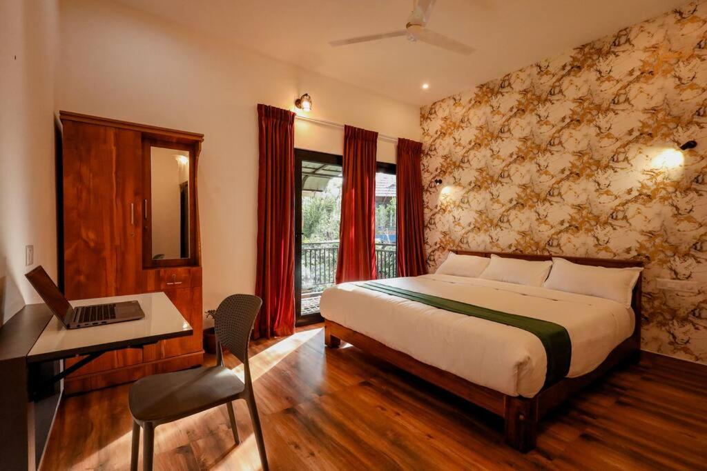 1 dormitorio con cama, escritorio y ordenador portátil en Cozy 3 BHK PoolVilla near Nagerhole National park., en Wayanad