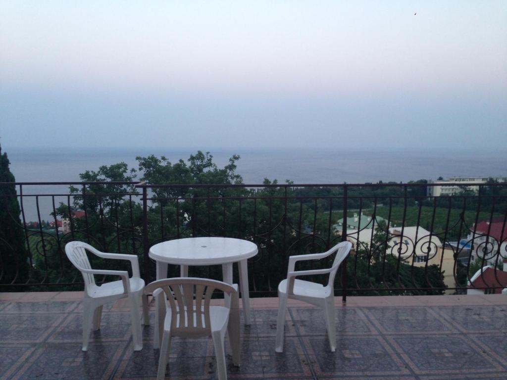 a table and chairs on a balcony with the ocean at Guest House Livadiya in Livadiya