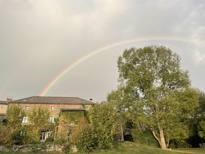 um arco-íris no céu sobre uma casa com uma árvore em L'ancien Relais de Poste*** em Saint-Dier-dʼAuvergne