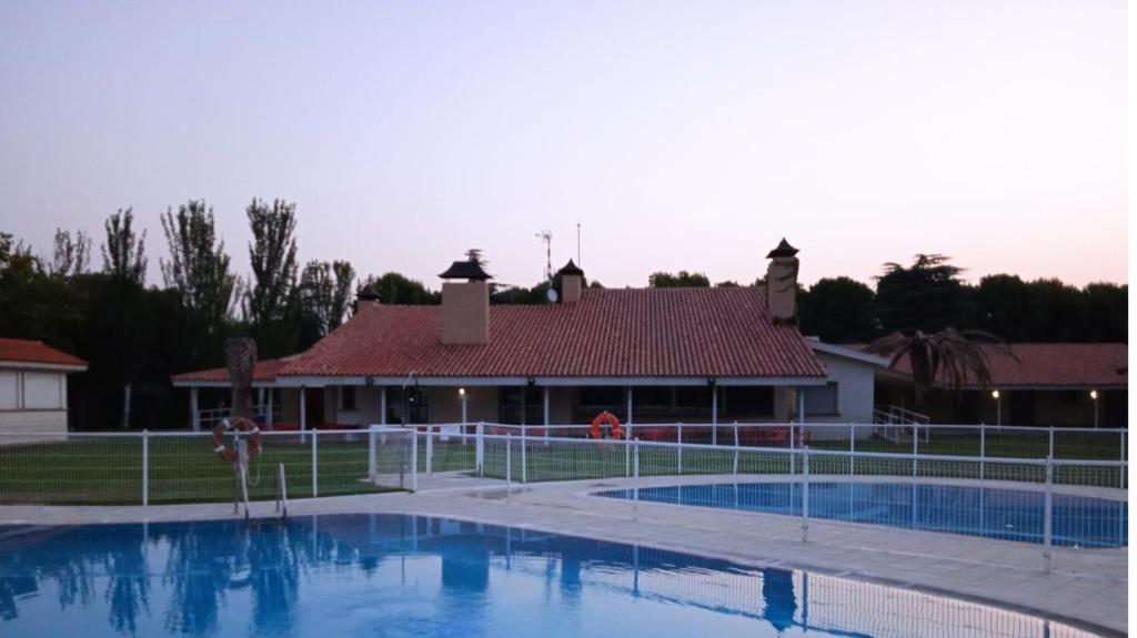 a swimming pool in front of a house at Bungalows Zaragoza Camping in Zaragoza