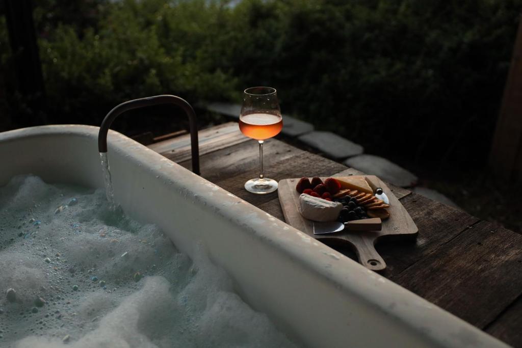 a glass of wine and a plate of food in a tub at The Sandy Sister in Dodges Ferry