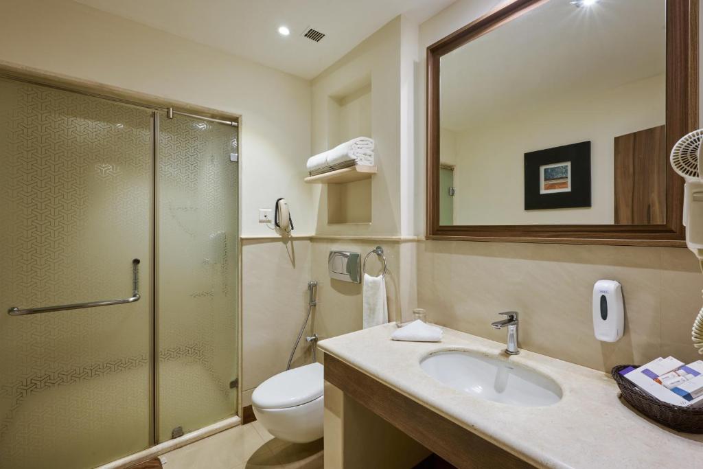 a bathroom with a shower and a sink and a toilet at Flora Airport Hotel and Convention Centre Kochi in Nedumbassery