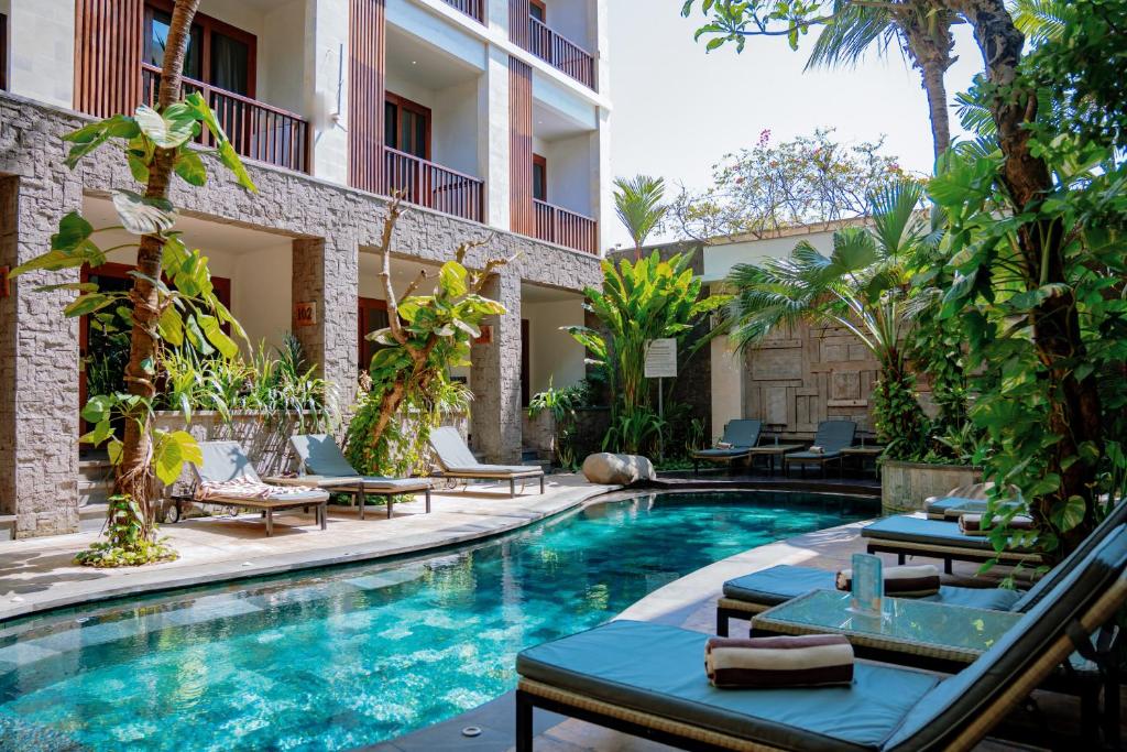 a pool at a hotel with lounge chairs and a resort at Akana Boutique Hotel in Sanur