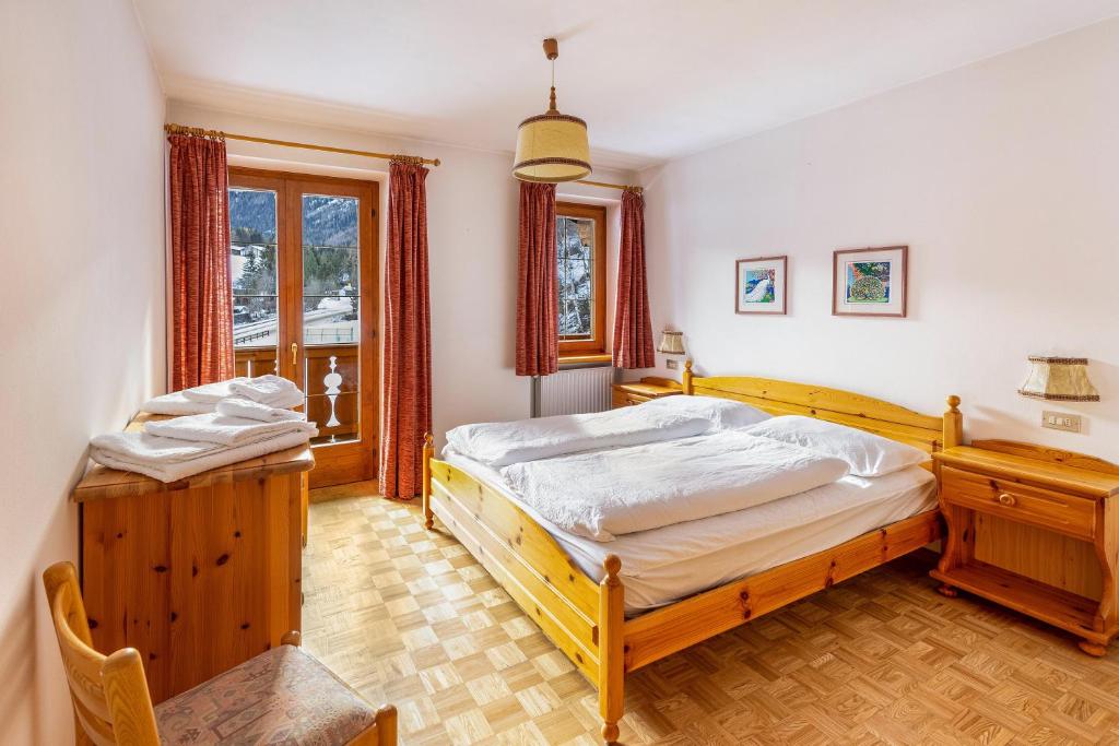 a bedroom with two beds and a desk and a window at Majon Garneté Buffaure 5 in Pozza di Fassa
