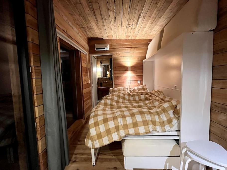 1 dormitorio con 1 cama con manta a cuadros en Les cabanes de Julie en Lissac et Mouret