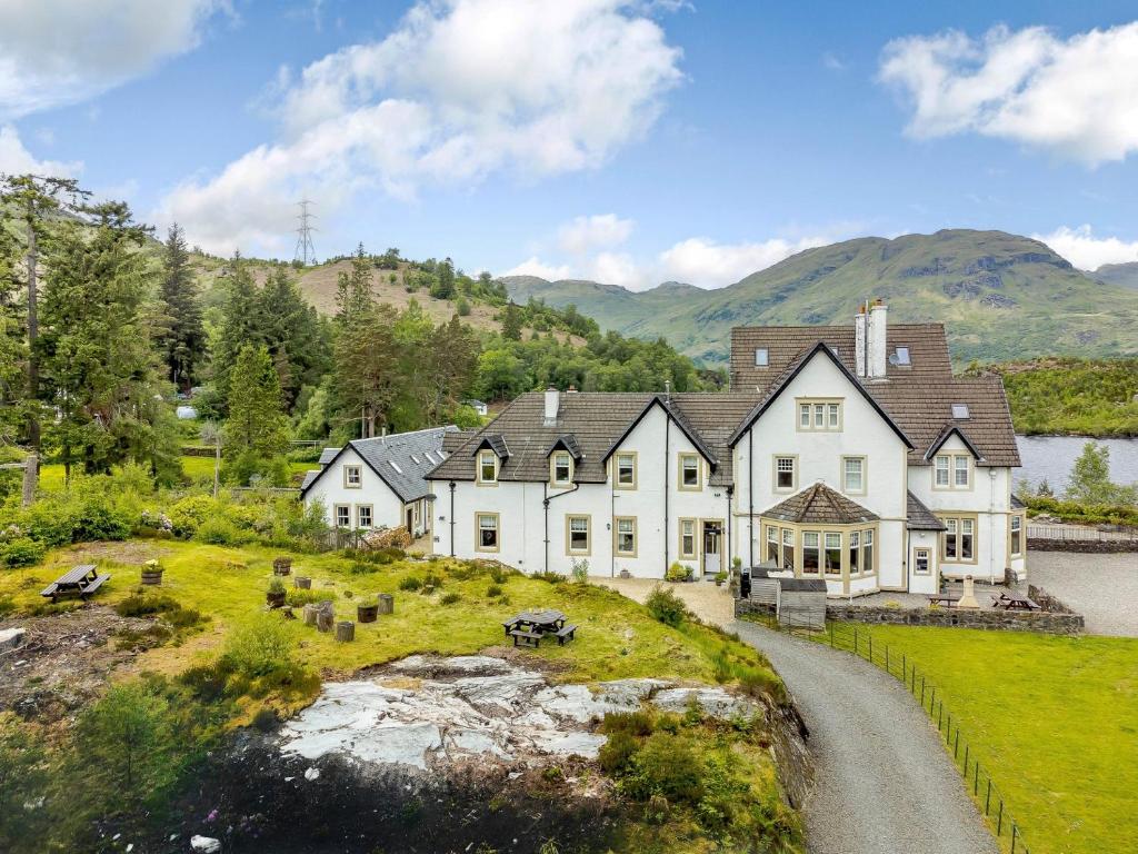 a large white house with mountains in the background at 4 bed in Loch Lomond 78669 in Stronachlachar