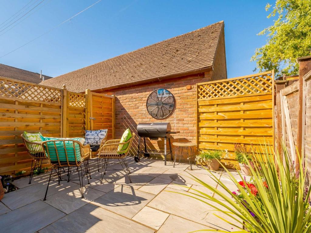 a patio with chairs and a grill and a fence at 2 Bed in Evesham 88722 in Bretforton
