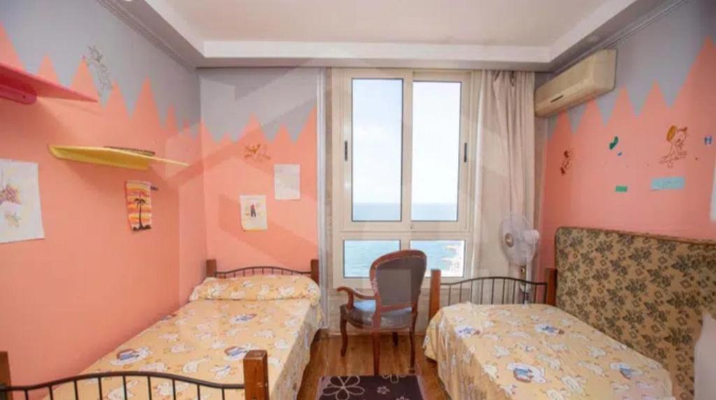 1 Schlafzimmer mit 2 Betten, einem Stuhl und einem Fenster in der Unterkunft بانوراما in Alexandria
