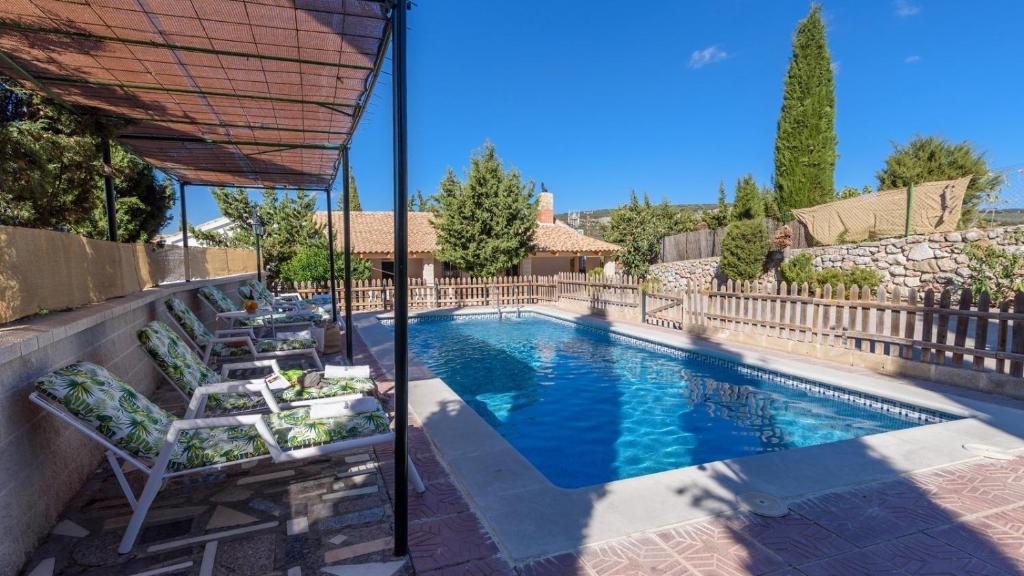 une piscine avec des chaises longues et une clôture dans l'établissement Casa de Paquita Montefrio by Ruralidays, à Montefrío