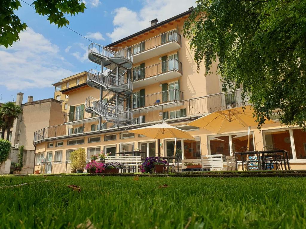 a large building with tables and umbrellas in front of it at Ostello Città di Rovereto in Rovereto