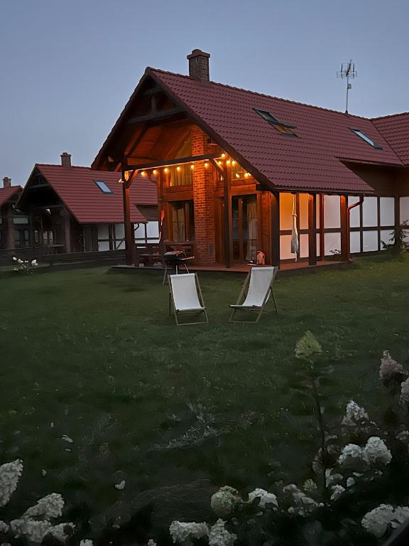 a couple of lawn chairs in front of a house at Ostoja Bukowo, Domek 9,1 'Stilia' in Borowy Młyn