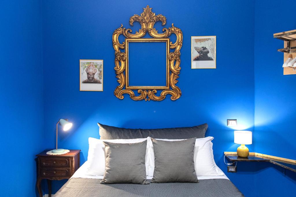 a blue bedroom with a bed with a mirror on the wall at Miracolo al Duomo Smart Accomodations in Naples