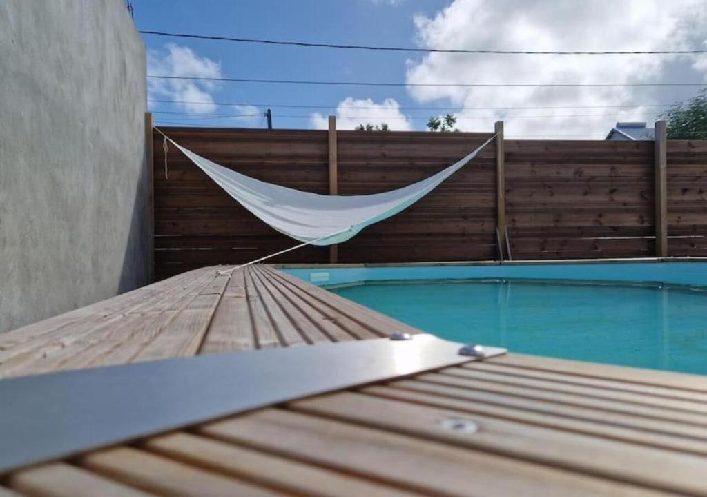 a hammock sitting on a table next to a pool at Maïlly - Charmante villa T5 in Capesterre-Belle-Eau