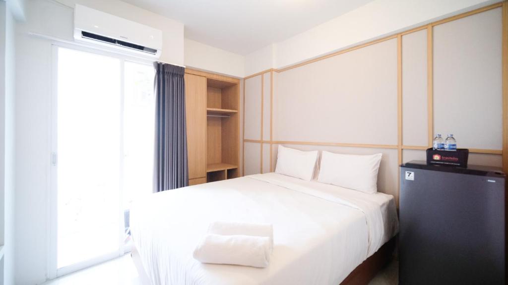 - une chambre avec un lit blanc et une fenêtre dans l'établissement Studio Apartment at Suncity Residence Sidoarjo near Suncity Mall By Travelio, à Sidoarjo