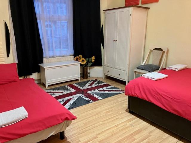 a bedroom with two beds and a chair and a window at Comfy rooms. Shared East London Homestay. in London