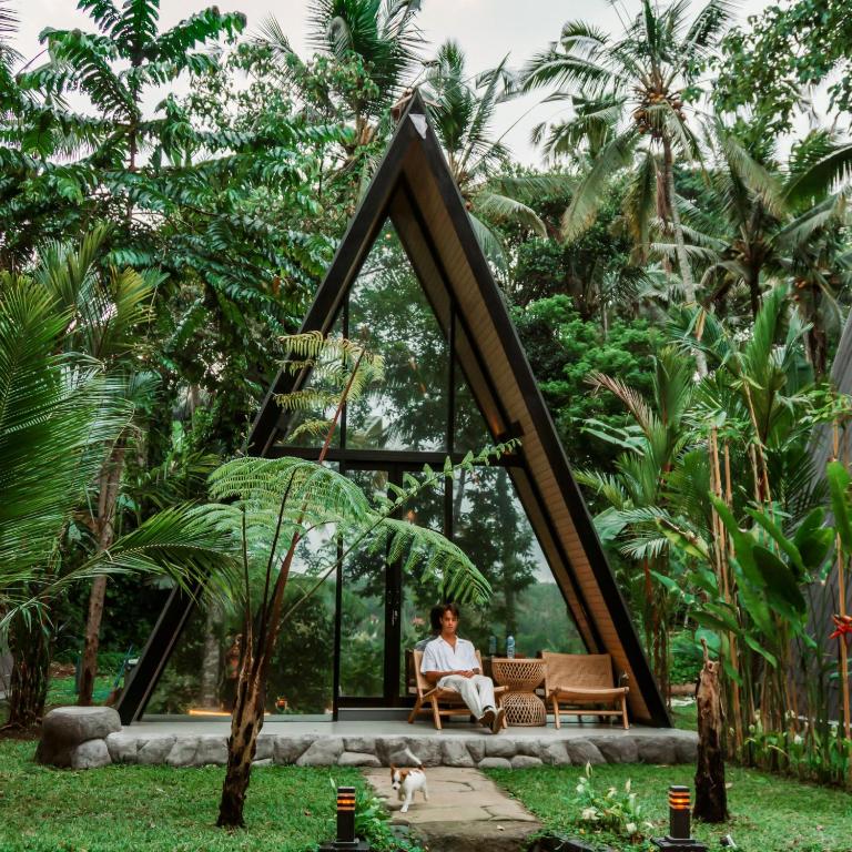 een persoon in een stoel in een kamer met bomen bij Delta Casa Ubud- Tiny Villas in Bali's Jungles in Gianyar
