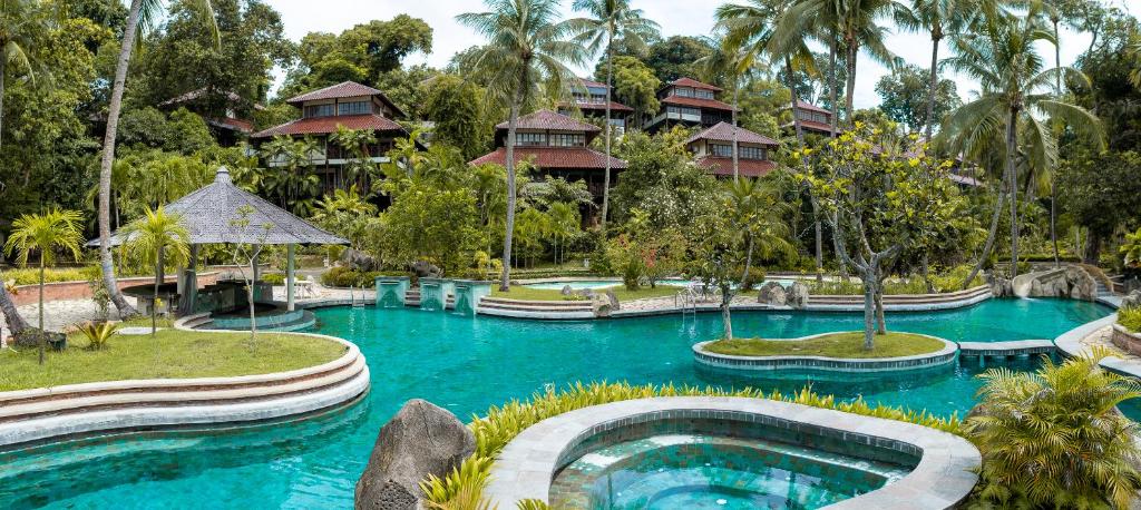 een zwembad in een resort met bomen en gebouwen bij Nongsa Village in Nongsa