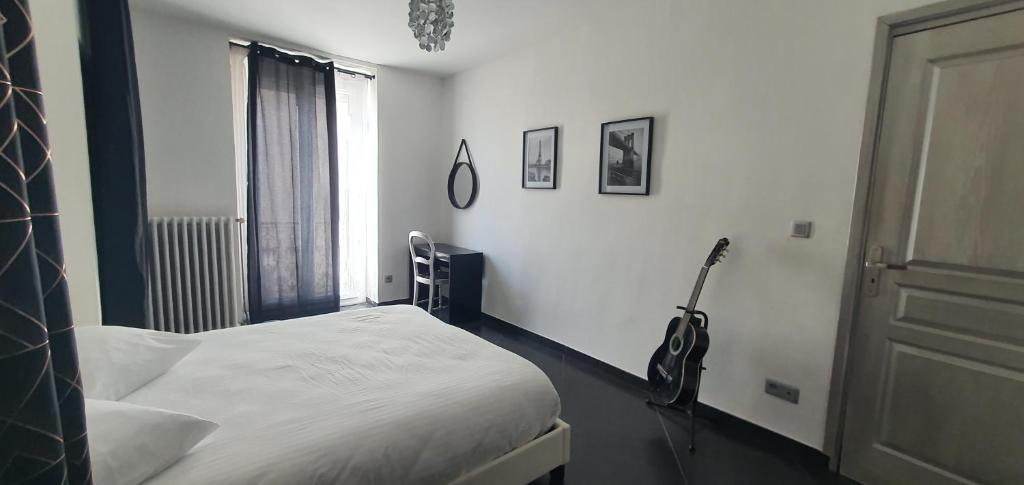 um quarto com uma cama e uma guitarra na parede em L'oiseau du paradis em Narbona