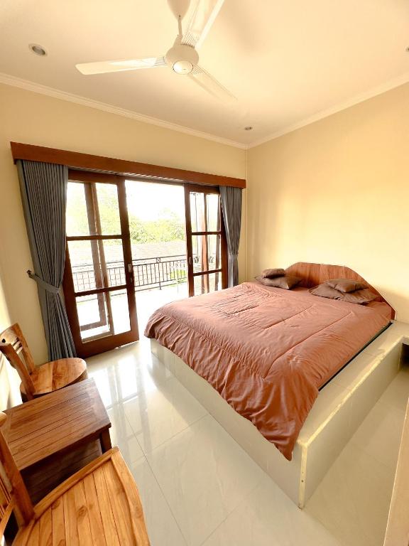 a bedroom with a bed and a large window at Ojek's Homestay in Ubud