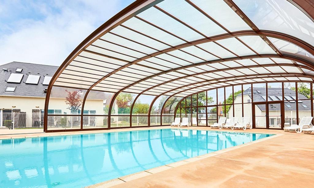 a large swimming pool with a retractable ceiling at Villa proche Deauville in Auberville