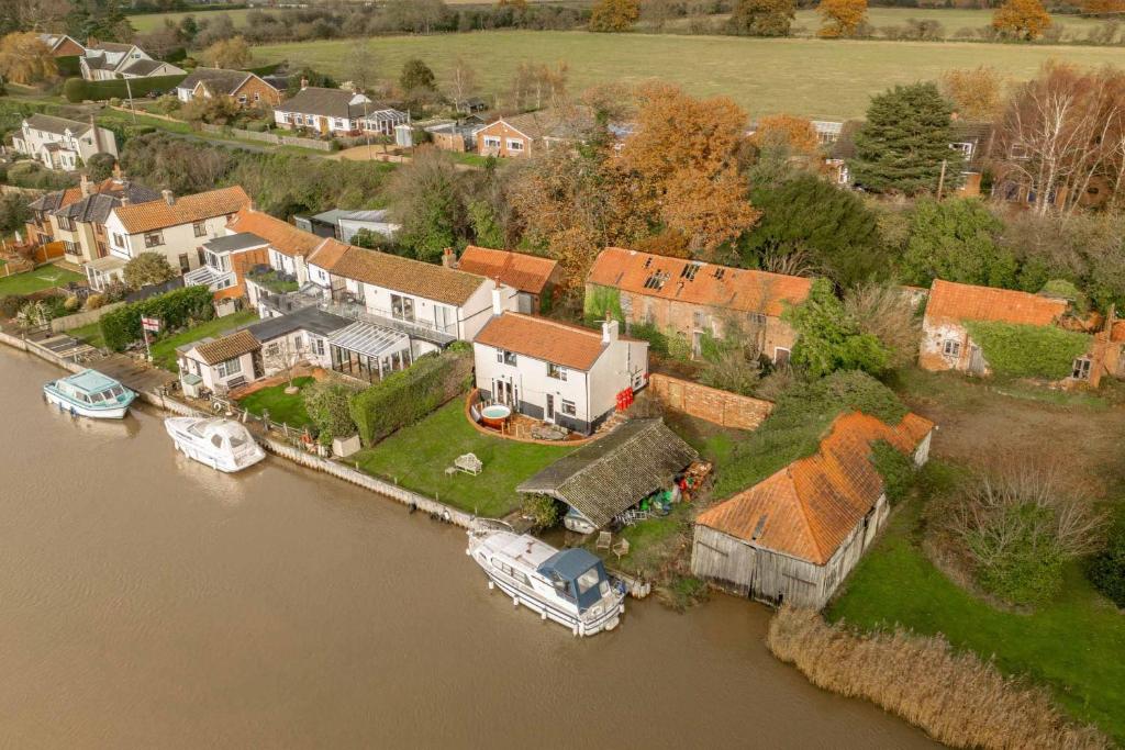 an aerial view of a house with boats in the water at Riverside Cottage - Norfolk Holiday Properties in Reedham