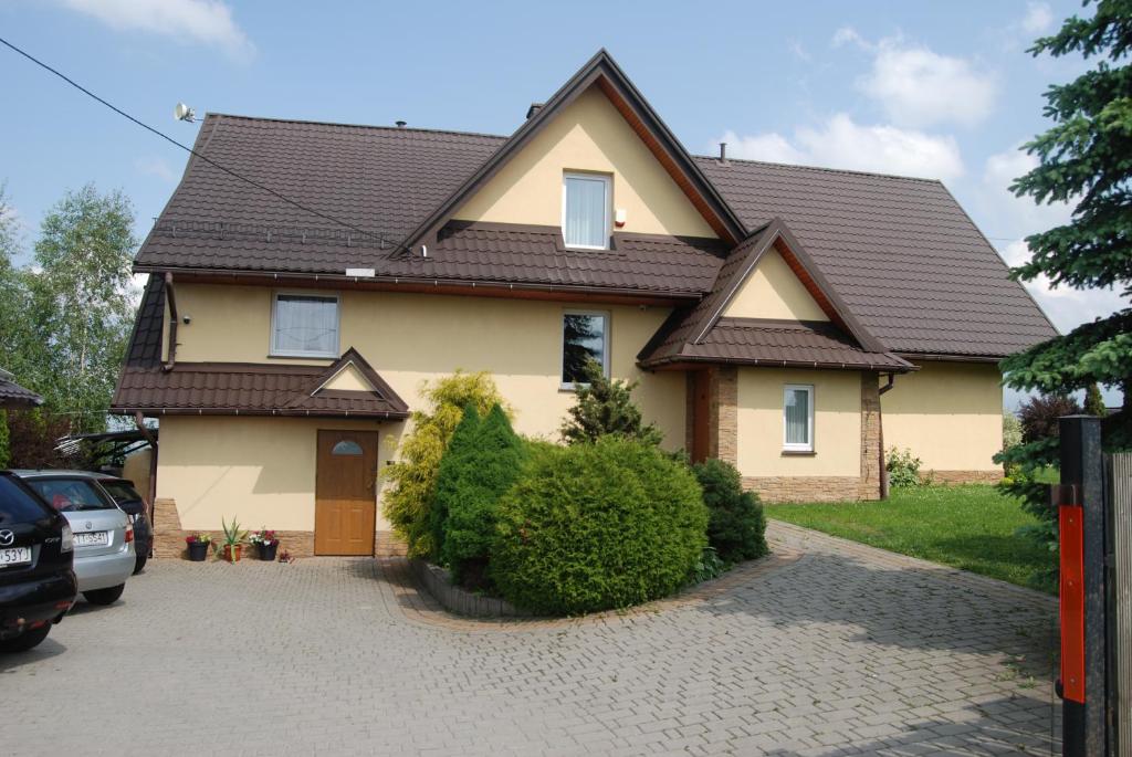 a yellow house with a brown roof at Pokoje u Rumcajsa in Ząb