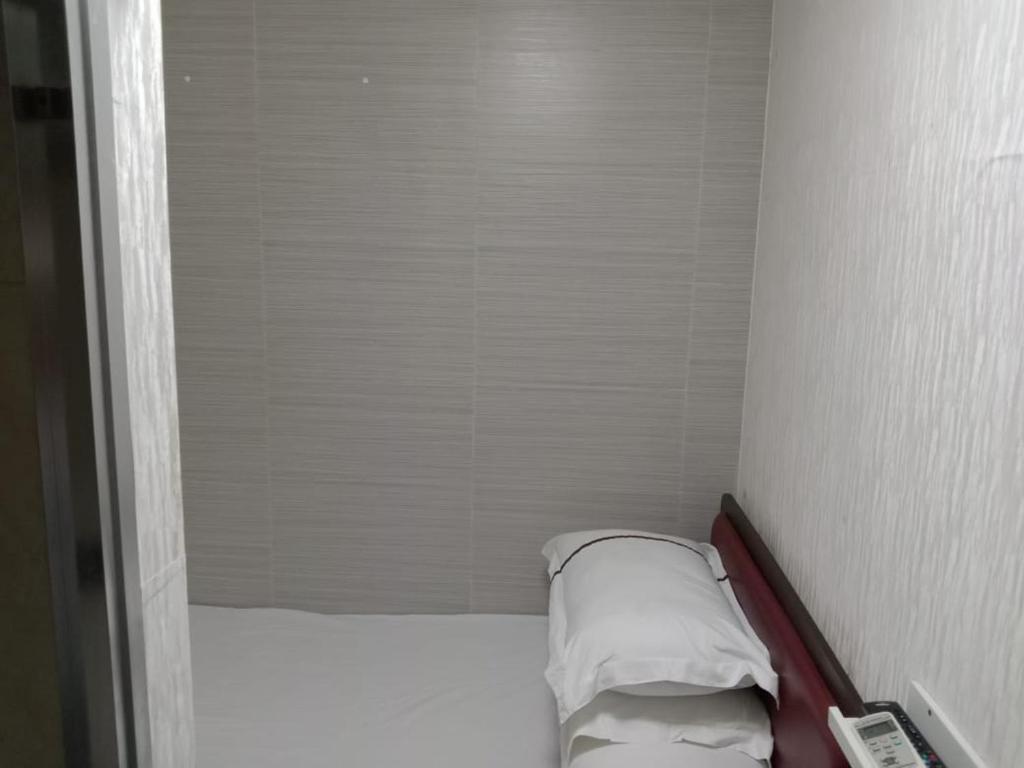 a small room with a bed with two pillows at 金源賓館 Golden Yuan Guest House in Hong Kong