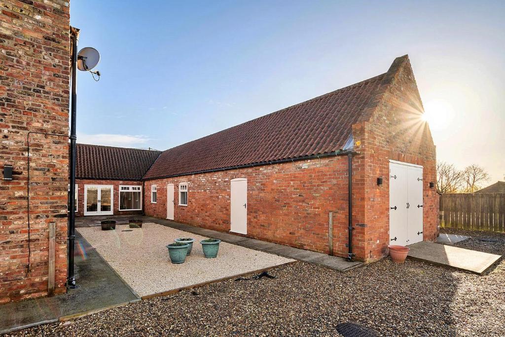 a brick building with a courtyard in front of it at Finest Retreats - South Barn in Winestead