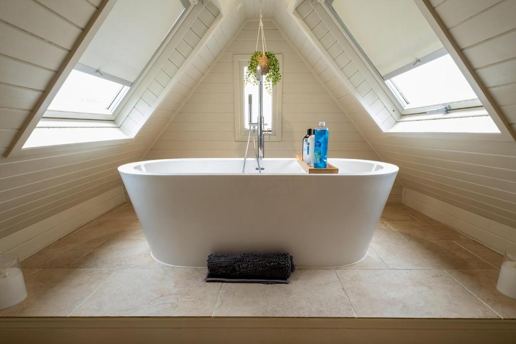 a white bath tub in a attic bathroom with skylights at Charming 2 bedroom property in Bury Saint Edmunds