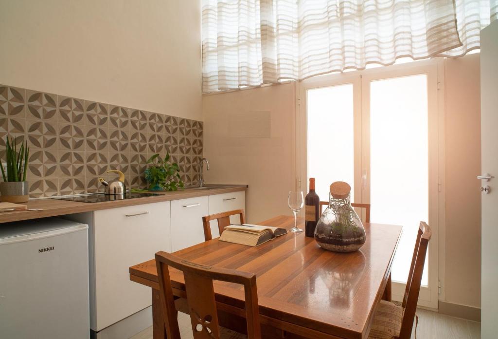 una cucina con tavolo in legno, sedie e finestra di Corte Nicolaiana Apartments by Wonderful Italy a Bari