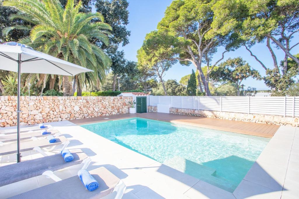 a swimming pool with lounge chairs and an umbrella at Villa Jomar by Sonne Villas in Cala Galdana