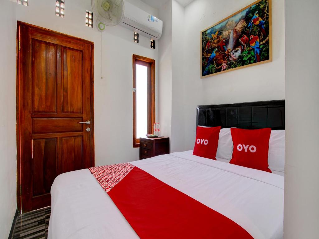 a bedroom with a bed with red pillows at OYO 93188 Soren Hotel And Coffee in Lawean