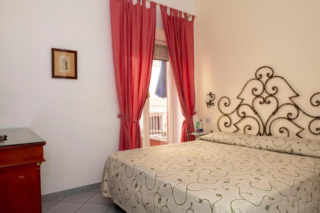 a bedroom with a bed with red curtains and a window at Palatium Mari in Capri