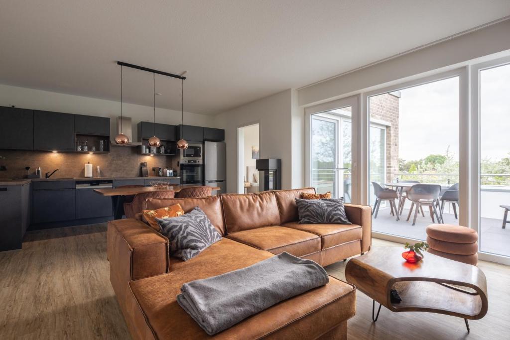 a living room with a brown couch and a kitchen at Park-Apartment Scharmützelsee Wohnung 12 in Wendisch Rietz