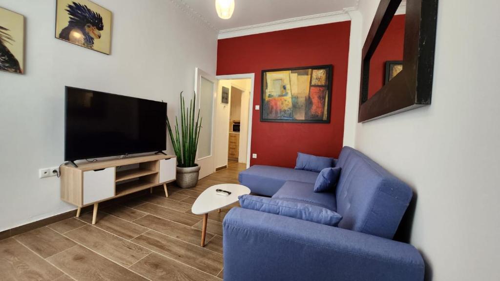 a living room with a blue couch and a tv at Gazi Apartment with Breakfast in Athens