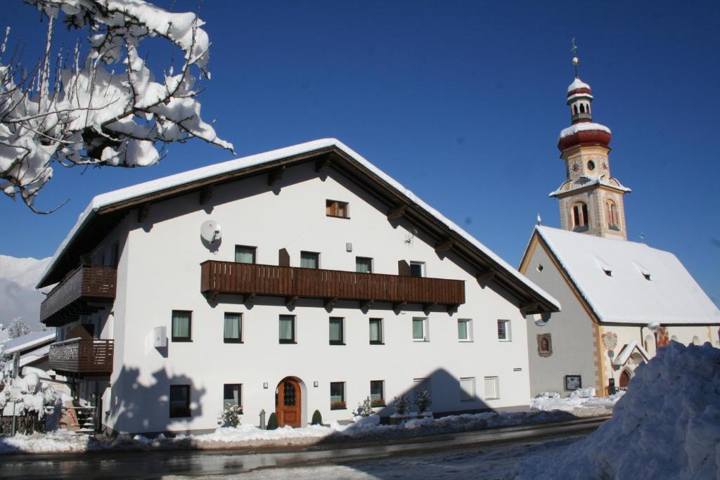 un edificio bianco con una torre dell'orologio nella neve di Gästehaus Elisabeth a Tulfes