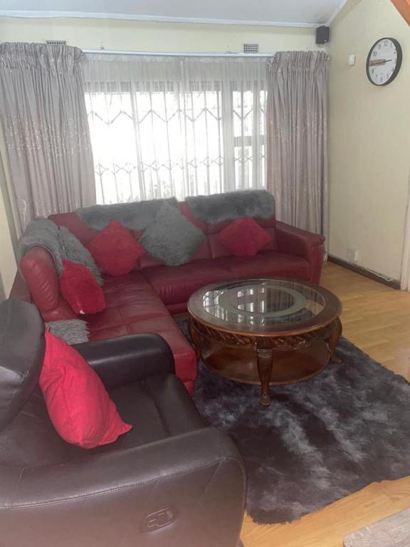 a living room with a red couch and a coffee table at Manors' Holiday Home in Durban