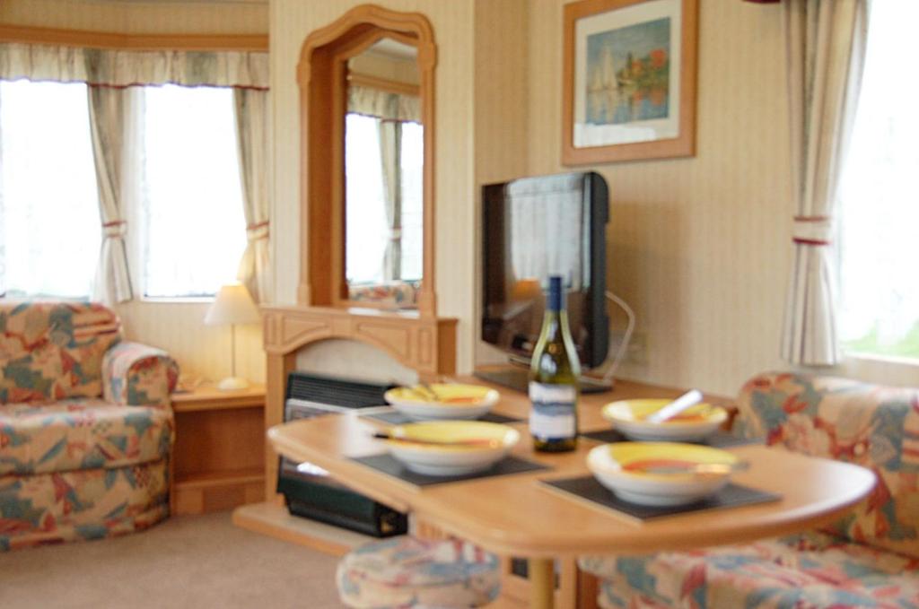 - un salon avec une table et des bols dans l'établissement Caravan 309 Bryn Y Mor Beach Side Park, à Tywyn