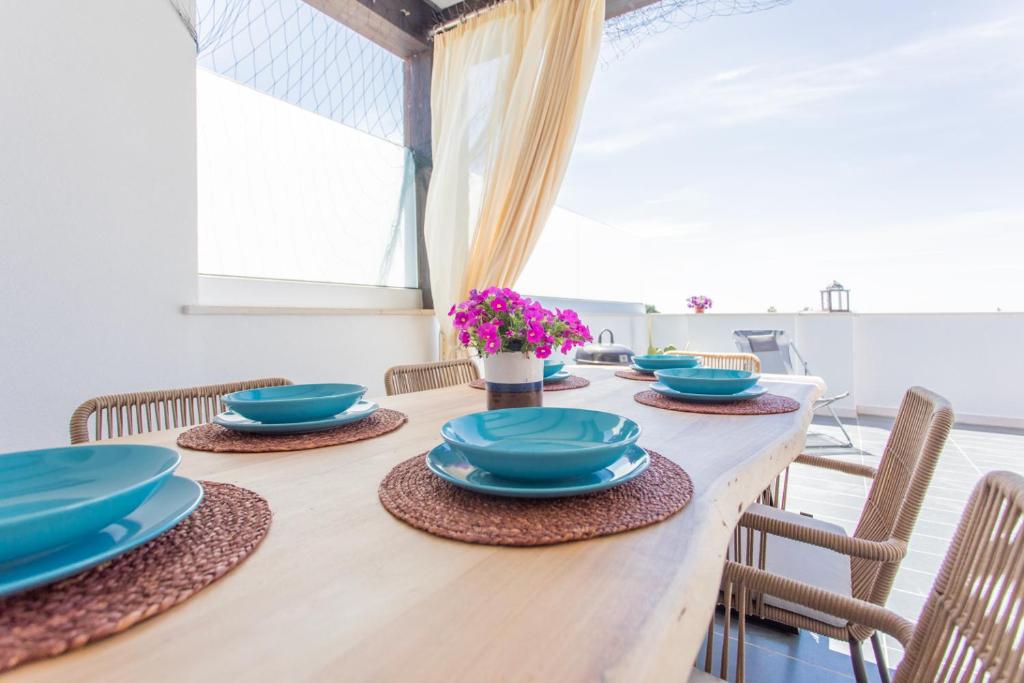 un tavolo in legno con piatti e sedie blu di Attico Dune Porto Cesareo a Porto Cesareo
