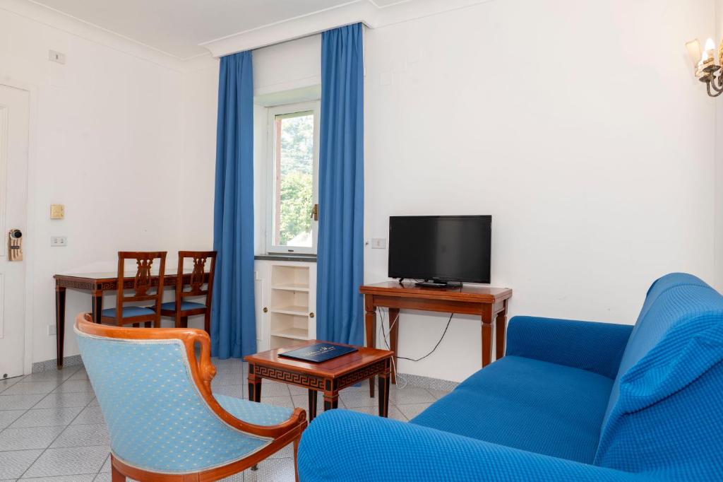 a living room with a blue couch and a tv at Palatium Mari in Capri